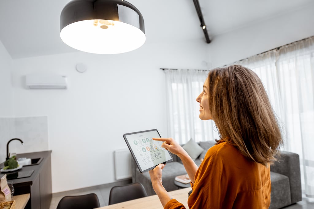 Woman holding an iPad and controlling the home lighting.
