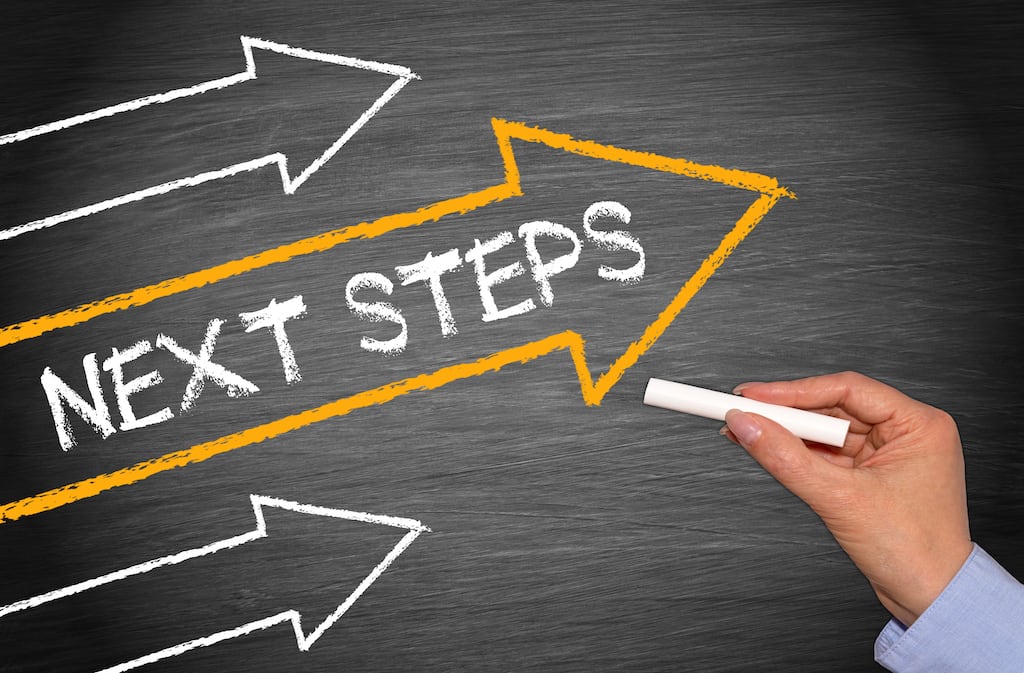 Image with "Next Steps" written on a blackboard with a hand holding chalk