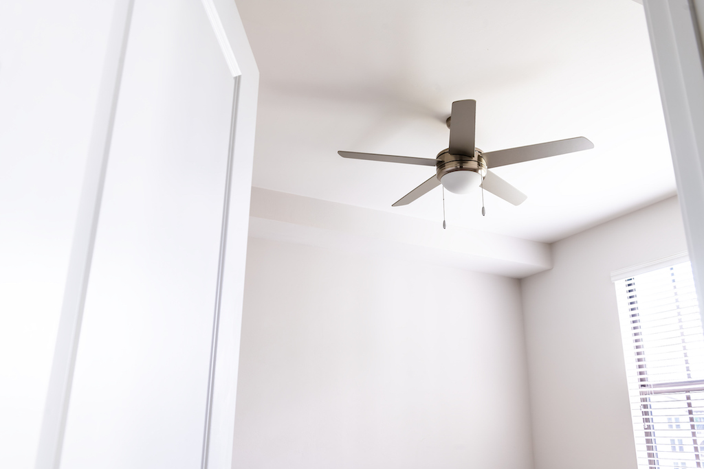 Ceiling fan in empty room with white walls.