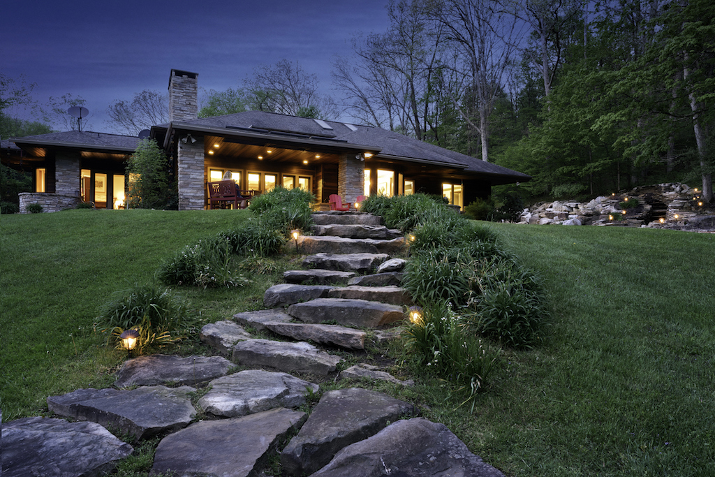 Backside exterior of a Prairie Style house with outdoor lighting at night.