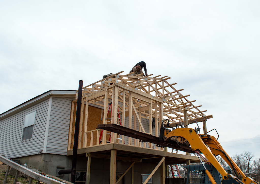 Workers framing a home addition to add onto the existing house and will be in need of electrical repair. 