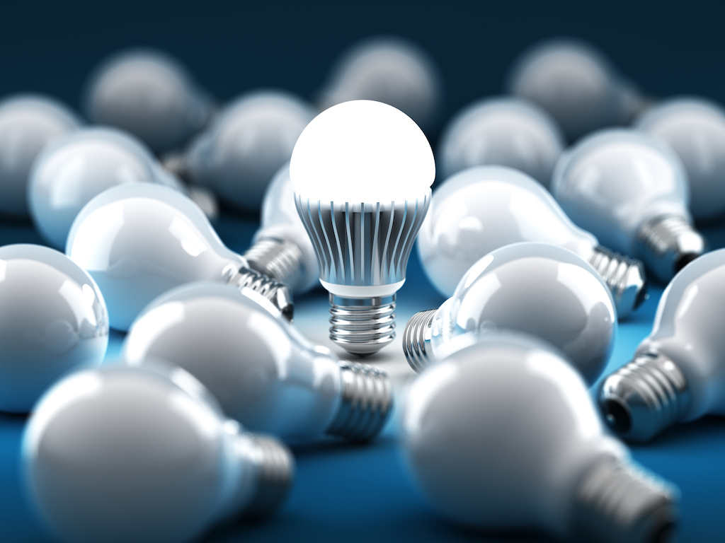 One lightbulb glowing among many dead bulbs. Concept of power outages and needing generator services.