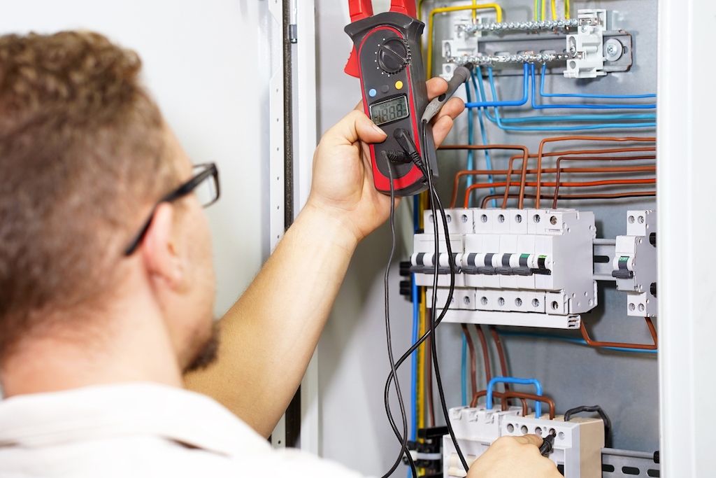 Man measuring voltage in an electrical panel. | Electrical Panel Upgrades