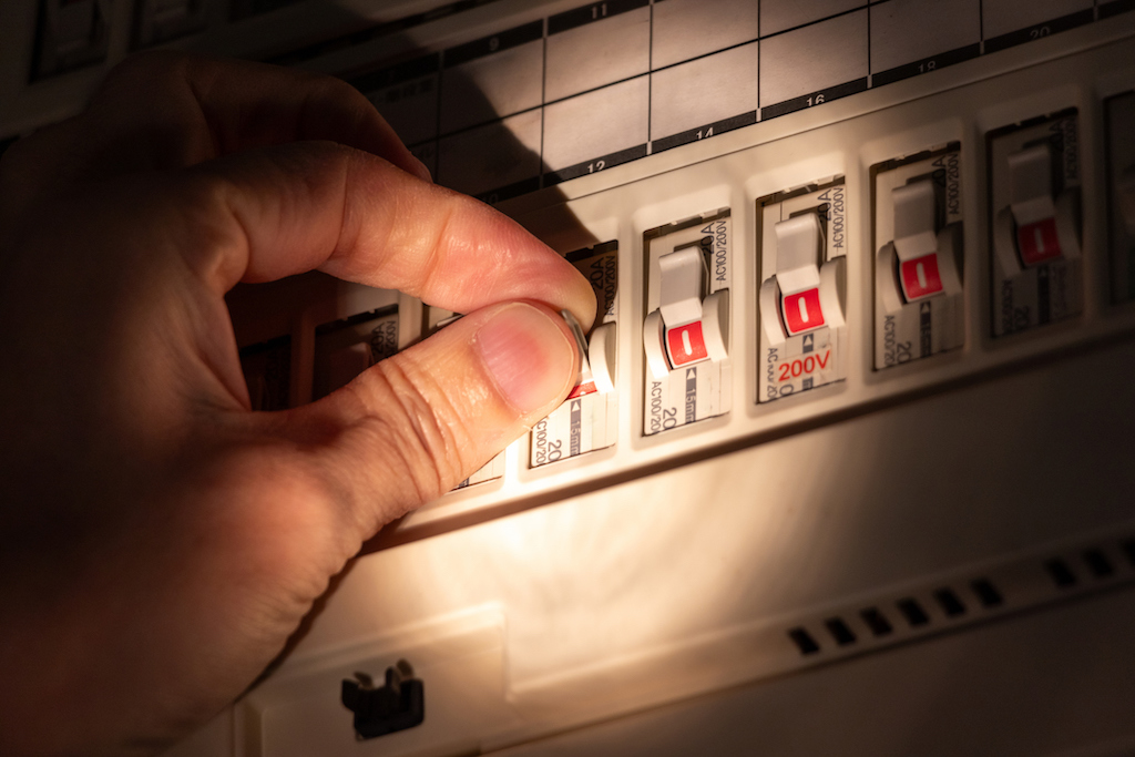 Person flipping breaker after breaker trips. | Electrical Panel Upgrades