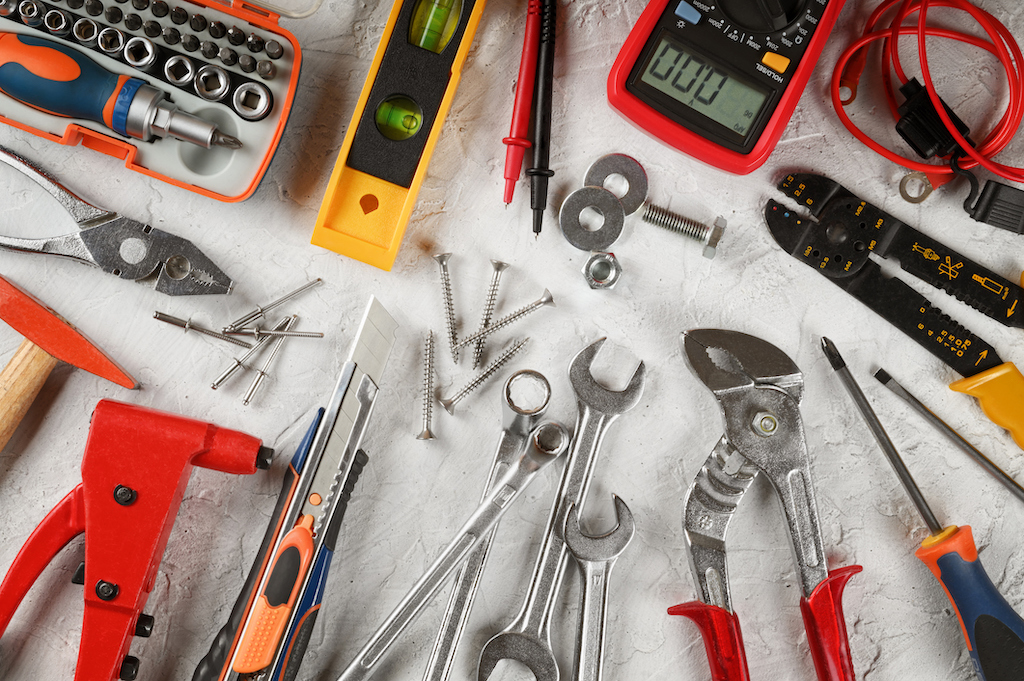 Variety of tools for residential electrician service on plain backdrop. 