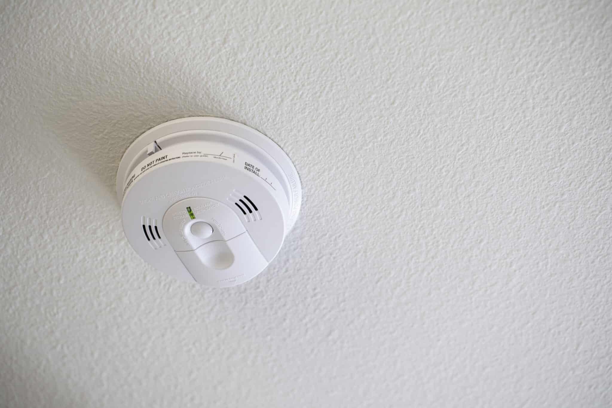 Hardwired smoke detectors on a white ceiling.